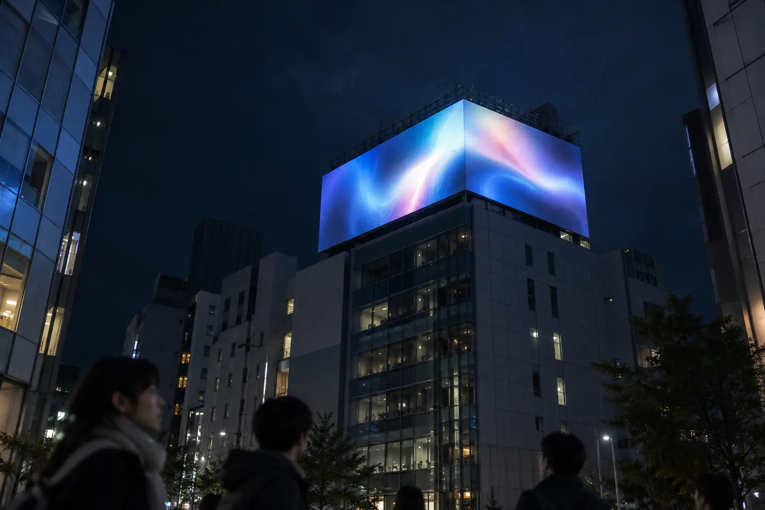 夜のビルの屋上に設置された大型の屋外LEDビジョンを、下から見上げた写真